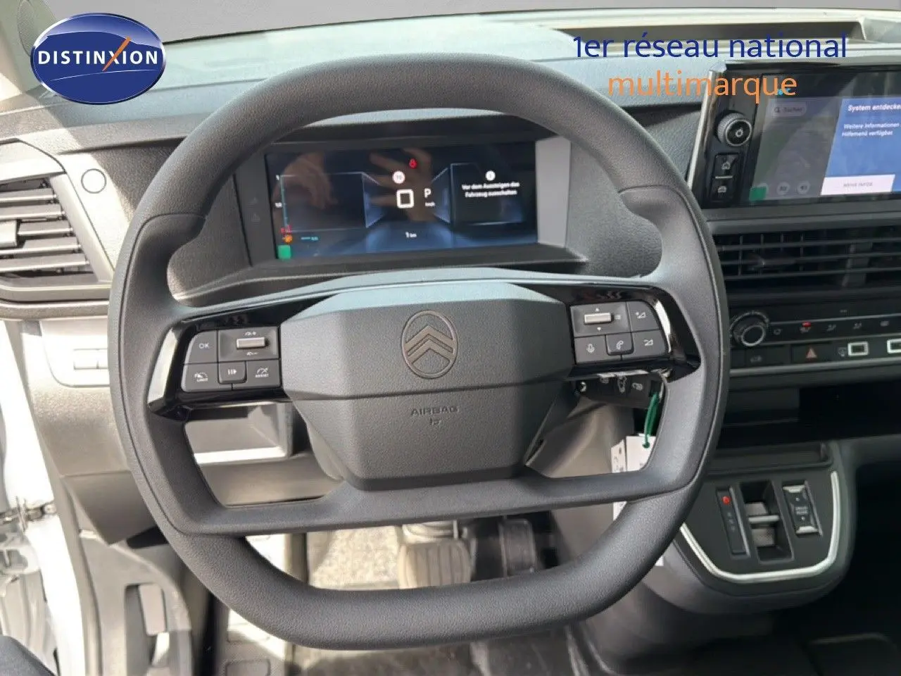 Vue intérieure centrée sur le volant noir de la Citroën Jumpy avec tableau de bord digital et console centrale visible.