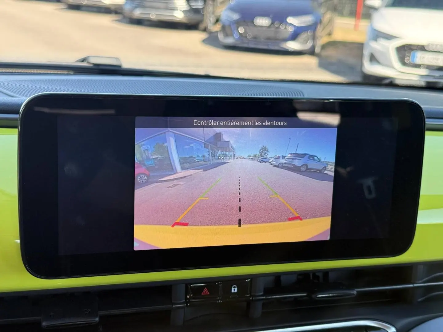 Écran tactile intérieur montrant la caméra de recul d'une Fiat 500 électrique jaune vue de face.