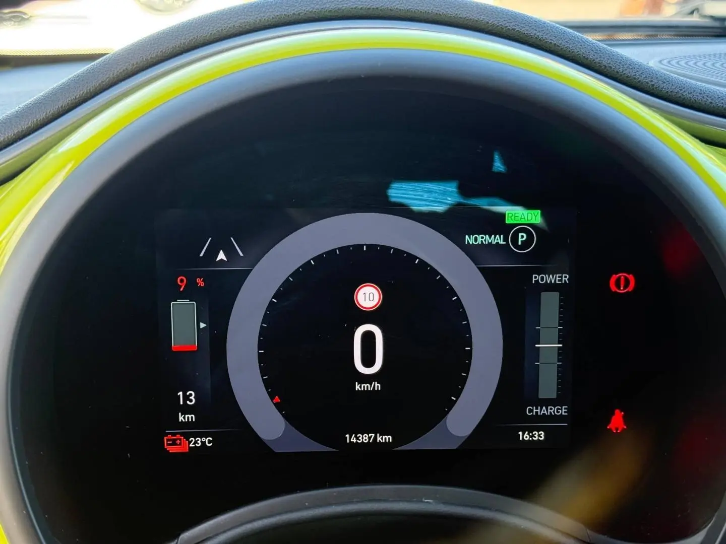 Vue rapprochée du tableau de bord numérique de la Fiat 500 électrique jaune, affichant la vitesse à 0 km/h.