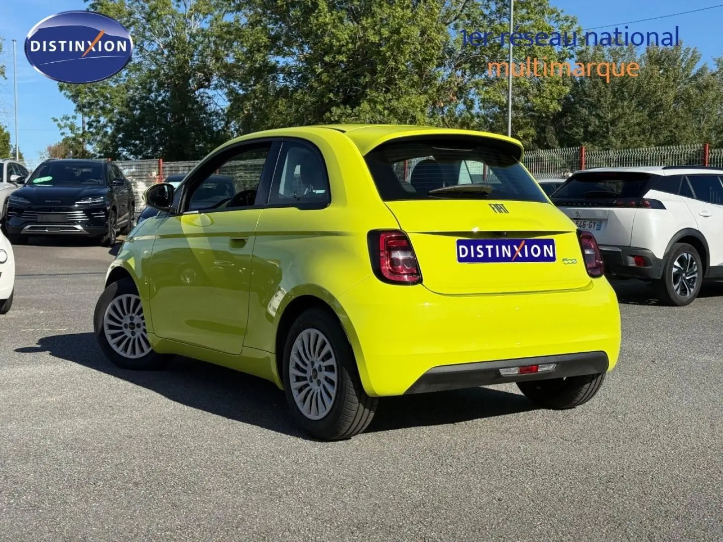 Vue 3/4 arrière droite d'une Fiat 500 électrique jaune Amalfi avec becquet et feux arrière LED, stationnée en extérieur.