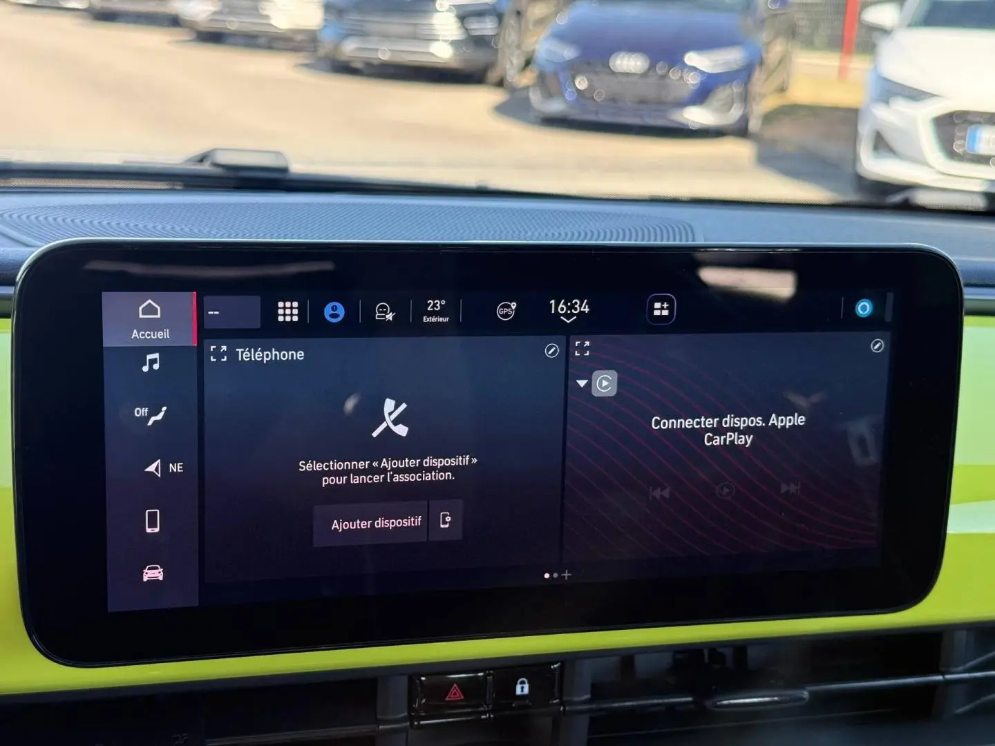 Écran tactile central de la Fiat 500 e jaune, affichant les options téléphone et Apple CarPlay, tableau de bord coloré.