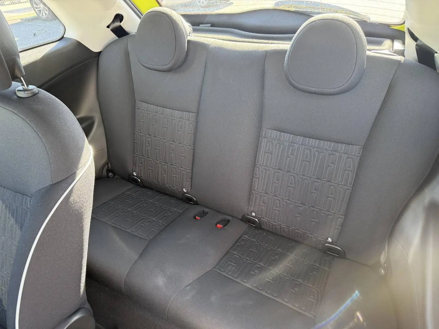 Vue intérieure de la banquette arrière noire avec motifs Fiat, dans une Fiat 500 e jaune 2024.