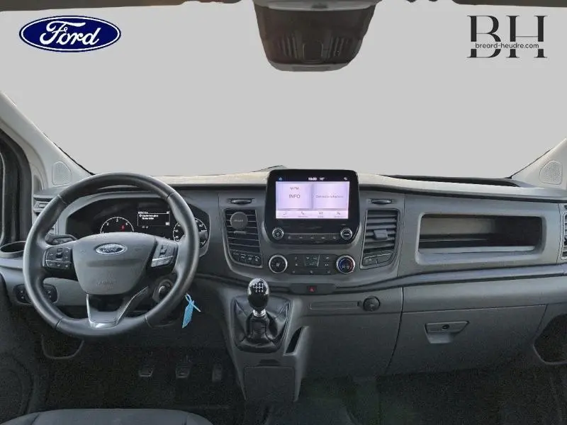 Vue intérieure frontale du tableau de bord du Ford Transit Custom gris, avec écran tactile et volant cuir multifonction.