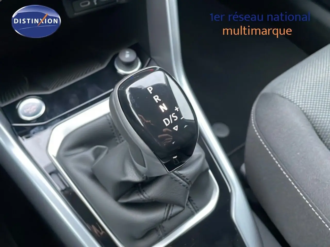 Gros plan sur le levier de vitesses automatique noir du Volkswagen T-Roc 1.5 TSI, intérieur tissu gris visible à droite.