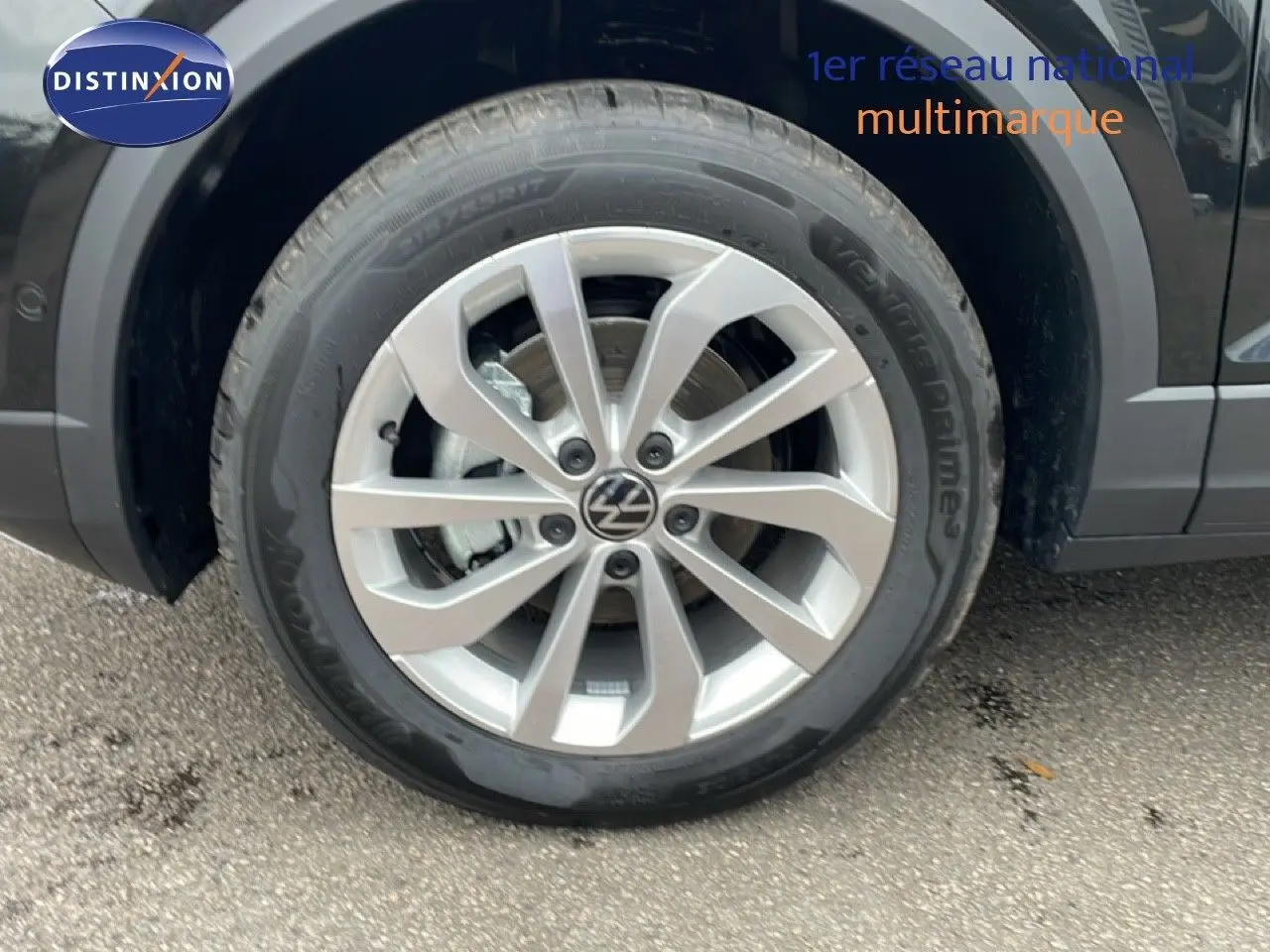 Gros plan sur la roue avant gauche d'un Volkswagen T-Roc noir grenadilla métal avec jante alliage argentée.