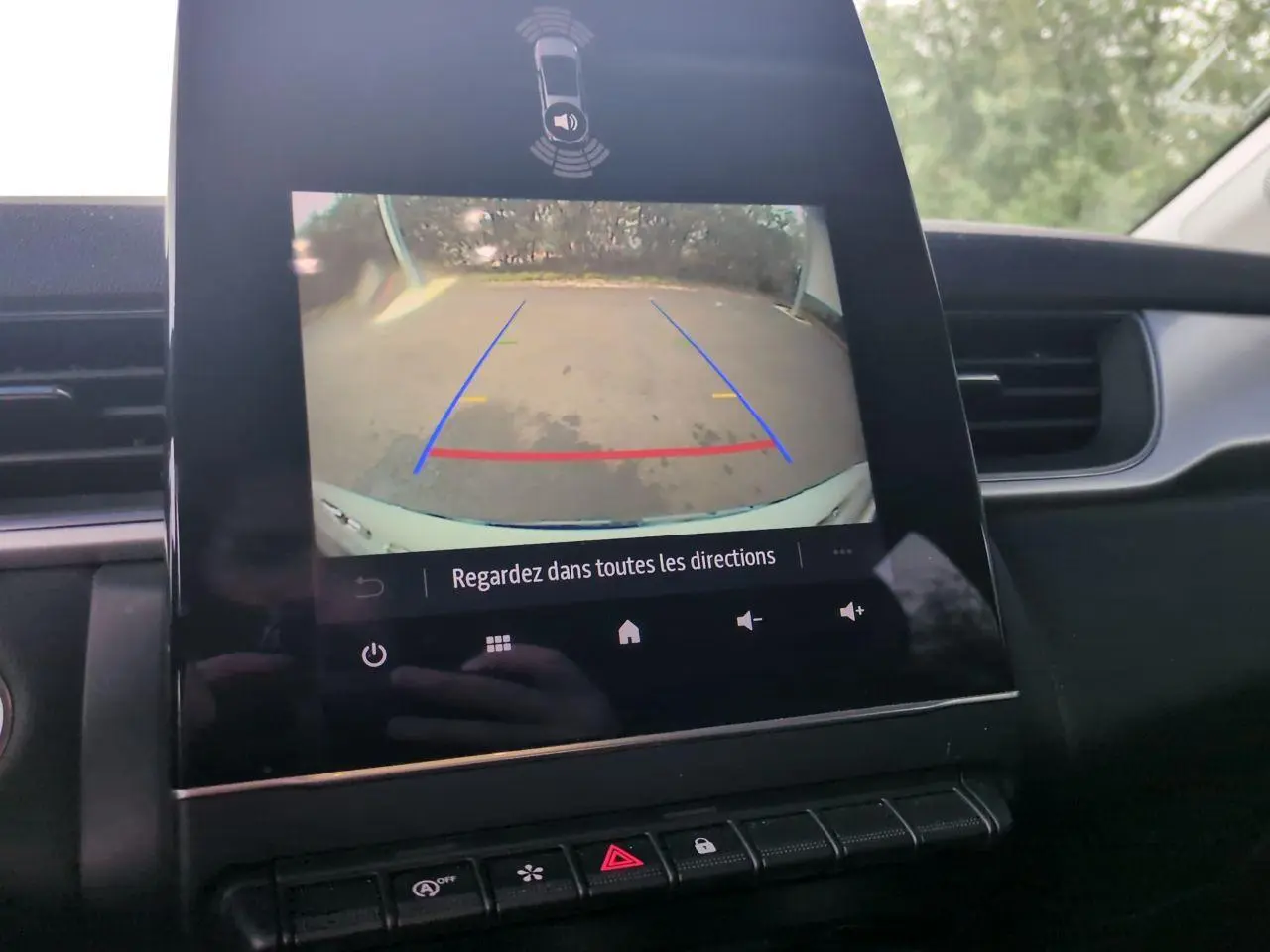 Vue intérieure du tableau de bord du Renault Captur blanc 2024 avec écran de caméra de recul affichant l'aide au stationnement.