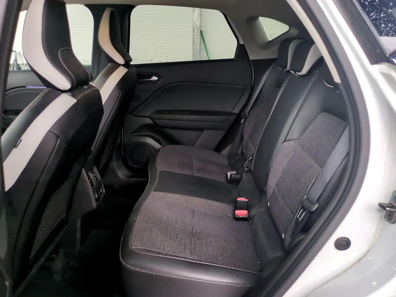 Vue intérieure côté droit des sièges arrière noirs et gris du Renault Captur blanc 2024 avec appuis-têtes réglables.