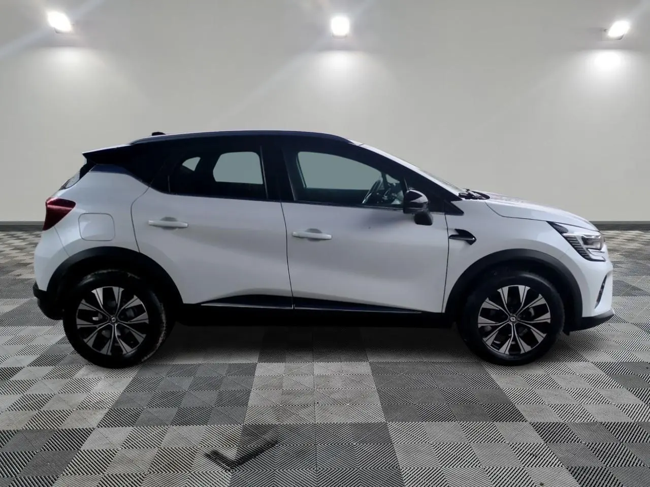 Profil côté gauche d'un Renault Captur blanc 2024 avec toit noir et jantes alliage bicolores dans un studio.