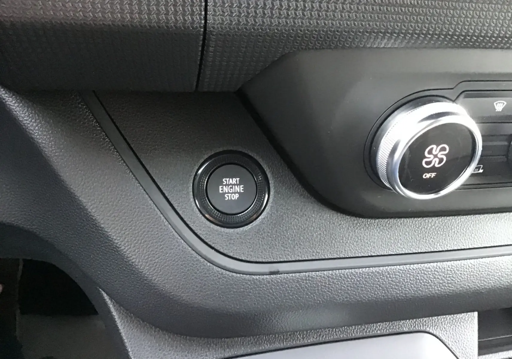 Détail du tableau de bord noir du Renault Trafic Fourgon 2025 montrant le bouton start/stop et la commande de ventilation.