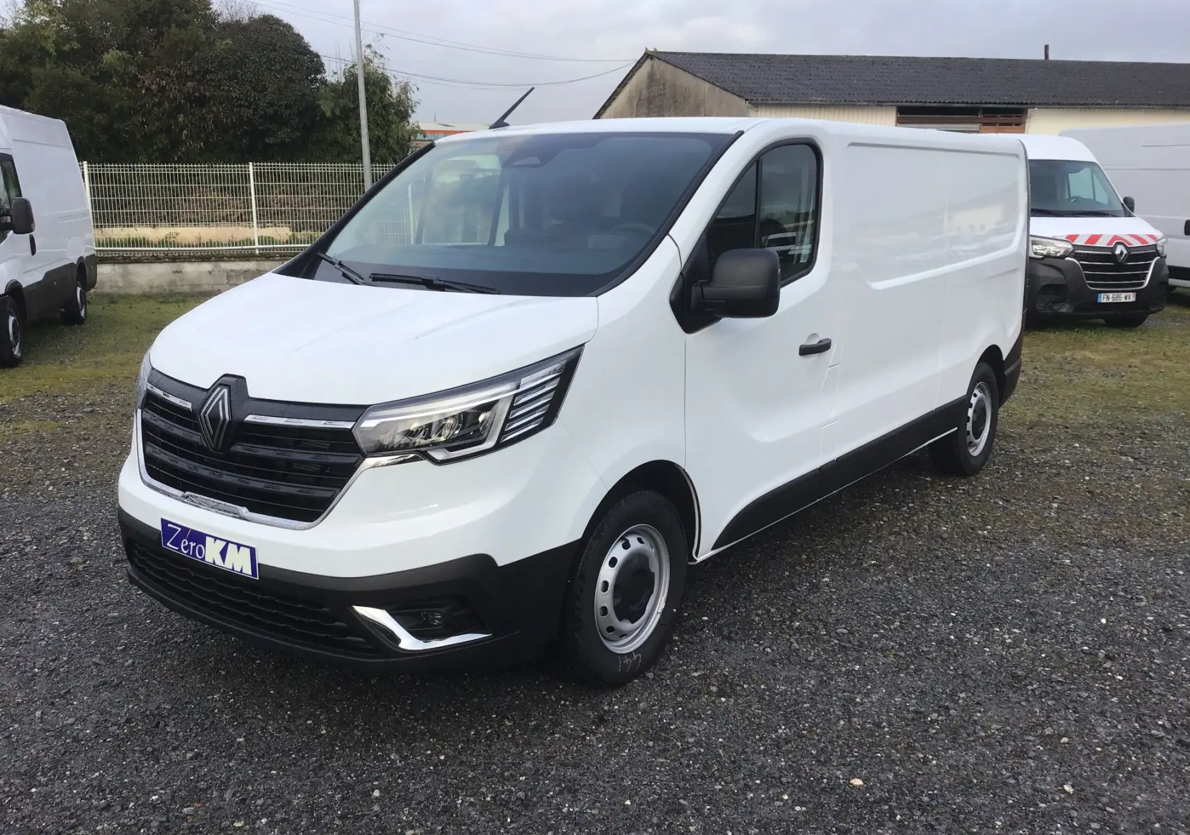 Renault Trafic Fourgon blanc en vue 3/4 avant droit, avec calandre noire et phares LED modernes.