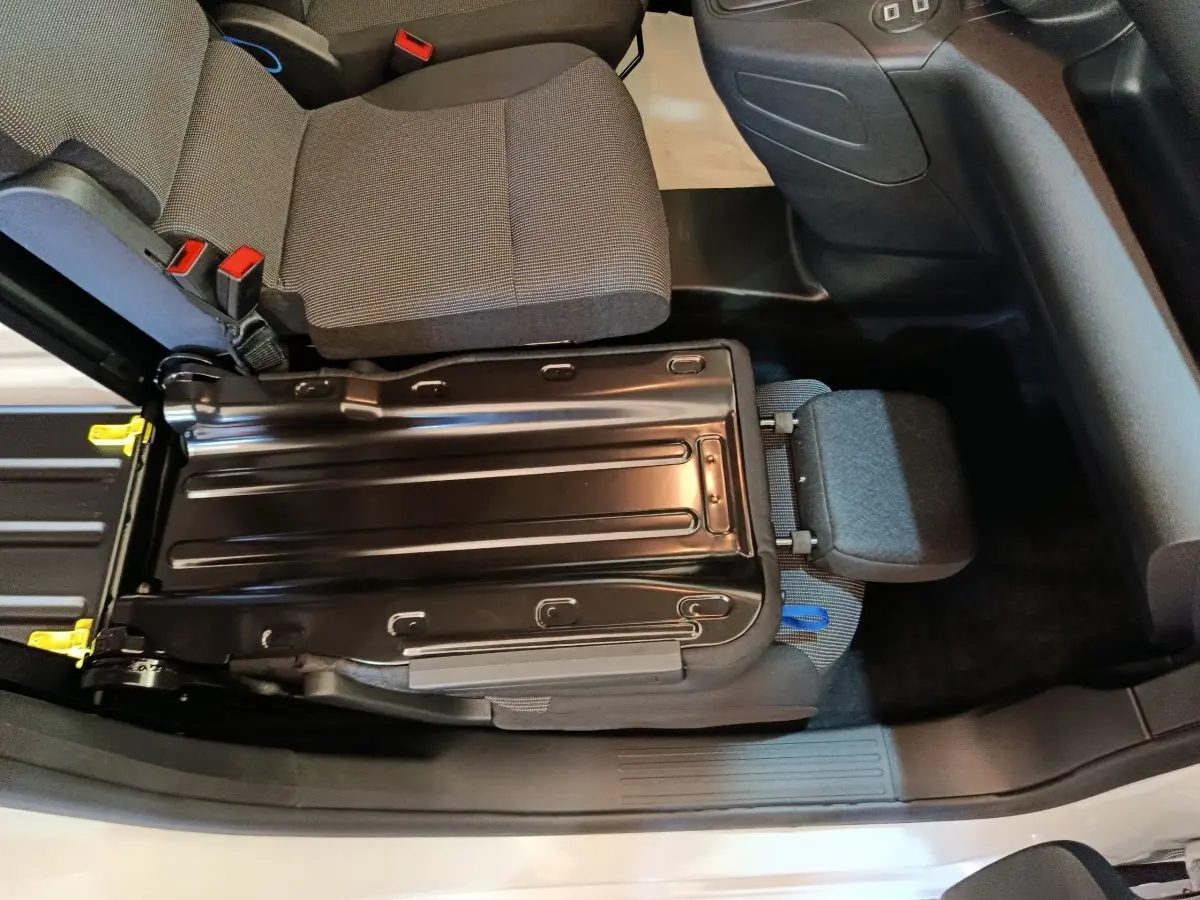Vue intérieure du siège passager avant relevé du Peugeot Partner blanc, montrant la structure métallique et l'assise grise.