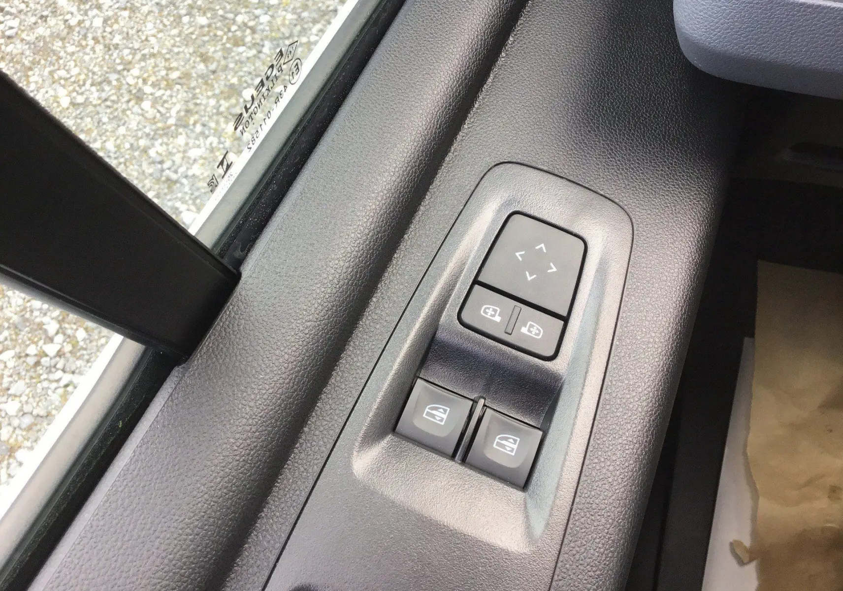 Gros plan sur les commandes de réglage des rétroviseurs et des vitres électriques côté conducteur du Renault Master blanc.