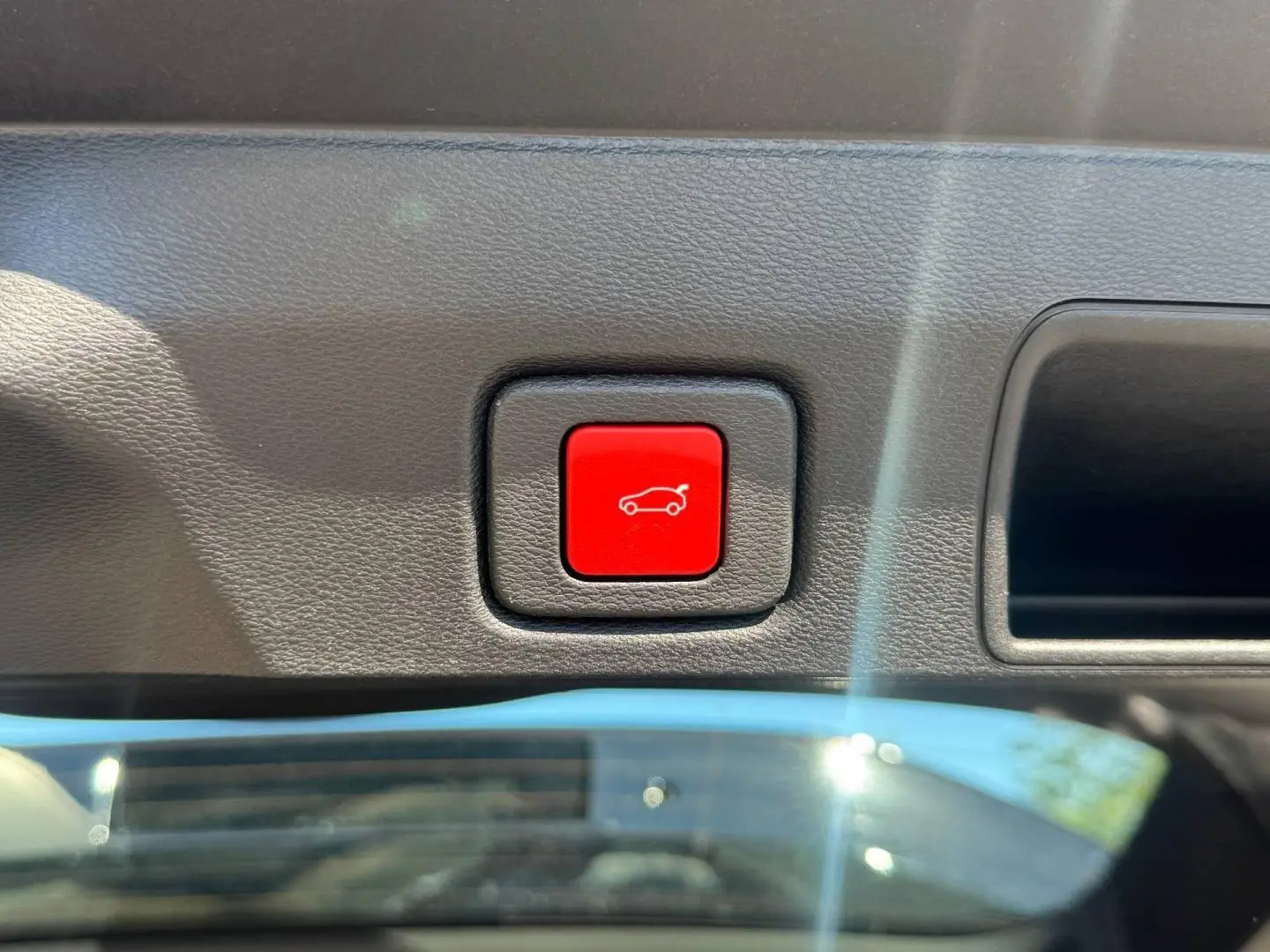 Bouton rouge d'ouverture du coffre sur la garniture intérieure d'un Jeep Compass 2026 couleur Vulcano.