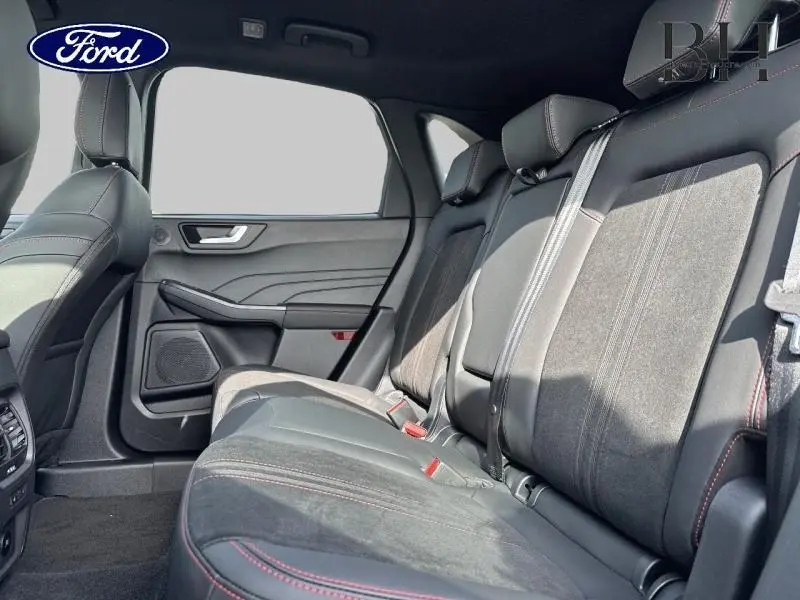 Vue latérale droite de l'intérieur arrière du Ford Kuga 2025 avec sièges en suédine noire et surpiqûres rouges.