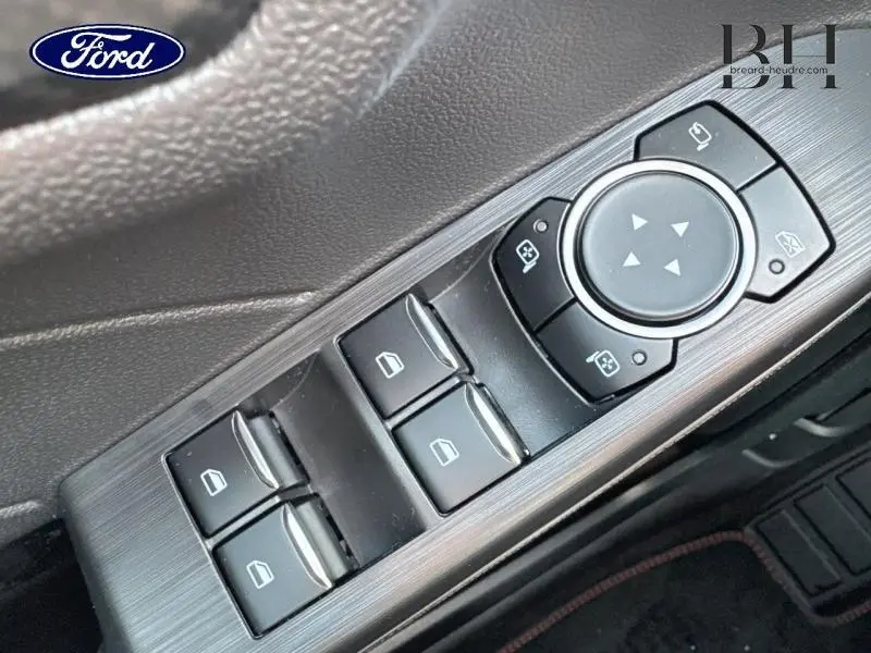 Gros plan sur les commandes de lève-vitres et réglage des rétroviseurs côté conducteur du Ford Kuga gris métallisé 2025.