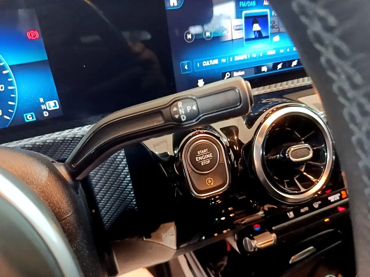 Gros plan intérieur sur la commande de boîte auto et bouton start/stop d'une Mercedes Classe A gris foncé, tableau de bord numérique.