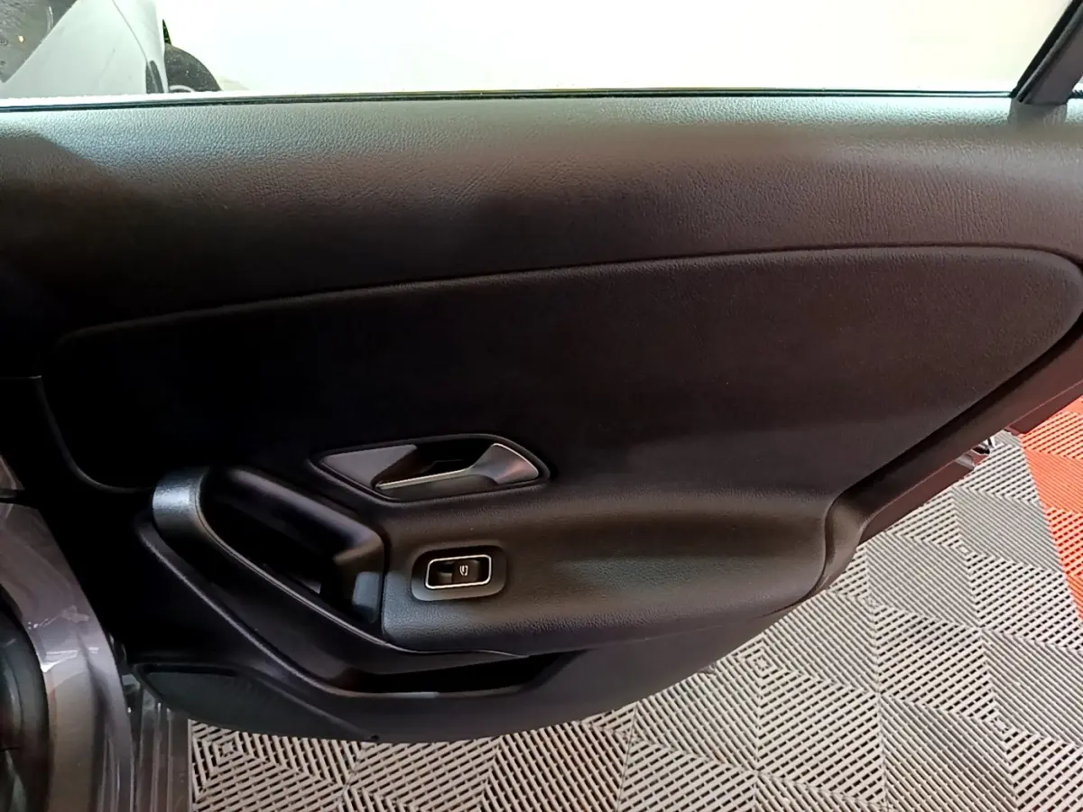 Intérieur de la porte côté gauche d’une Mercedes Classe A 180 d Business Line gris foncé, avec poignée et bouton de vitre électrique.