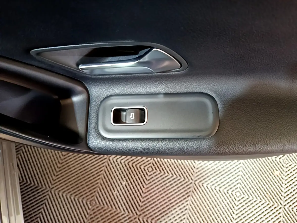 Détail de la commande de lève-vitre électrique sur la porte intérieure côté gauche d’une Mercedes Classe A gris foncé.