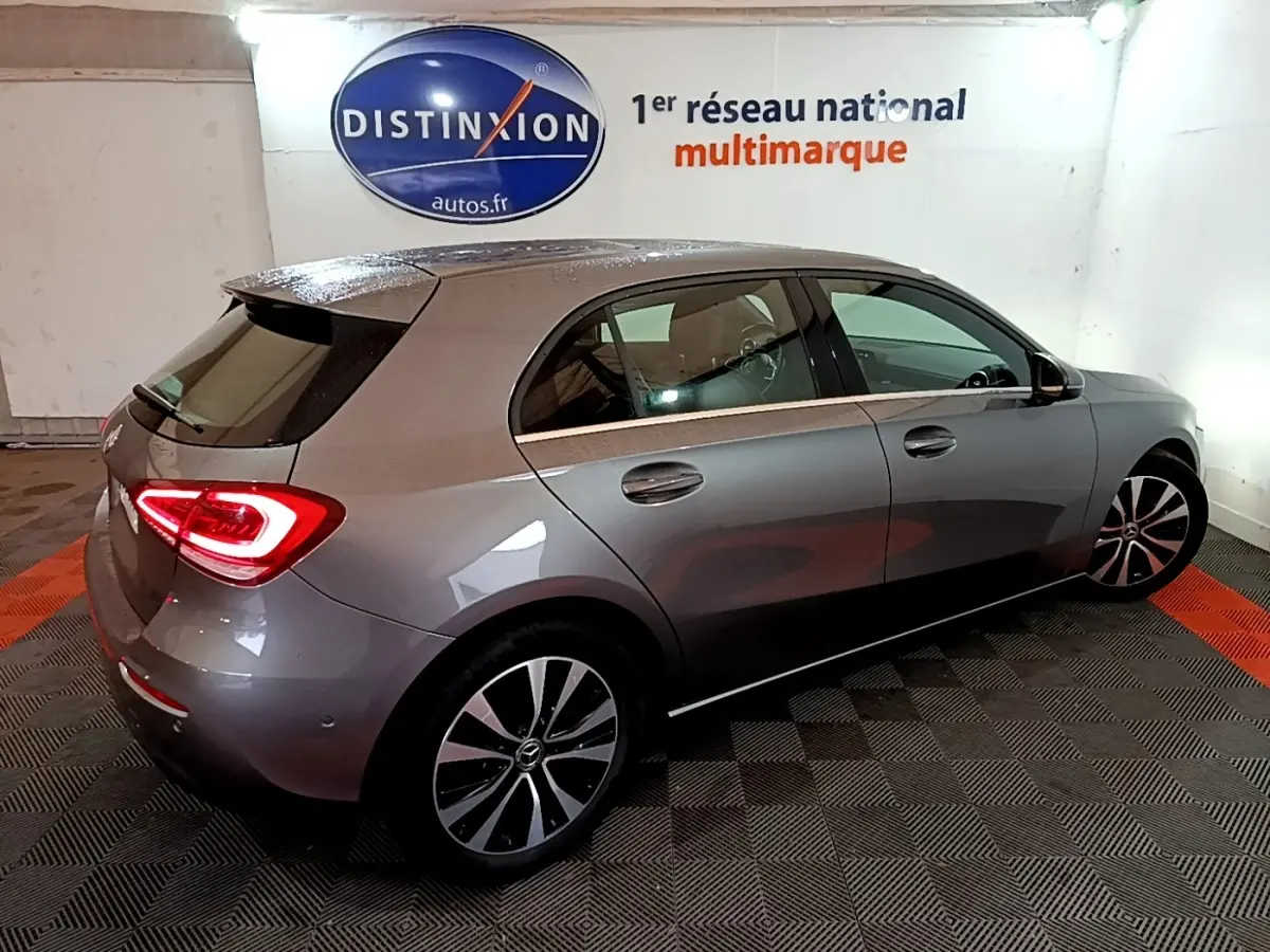 Mercedes Classe A 180 d Business Line gris foncé vue 3/4 arrière droit avec feux arrière allumés en intérieur.