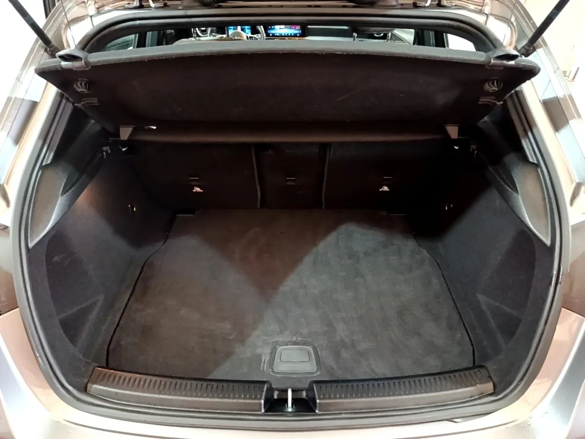 Coffre ouvert vu de l'arrière d'une Mercedes Classe A gris foncé, montrant l'espace de chargement vide.