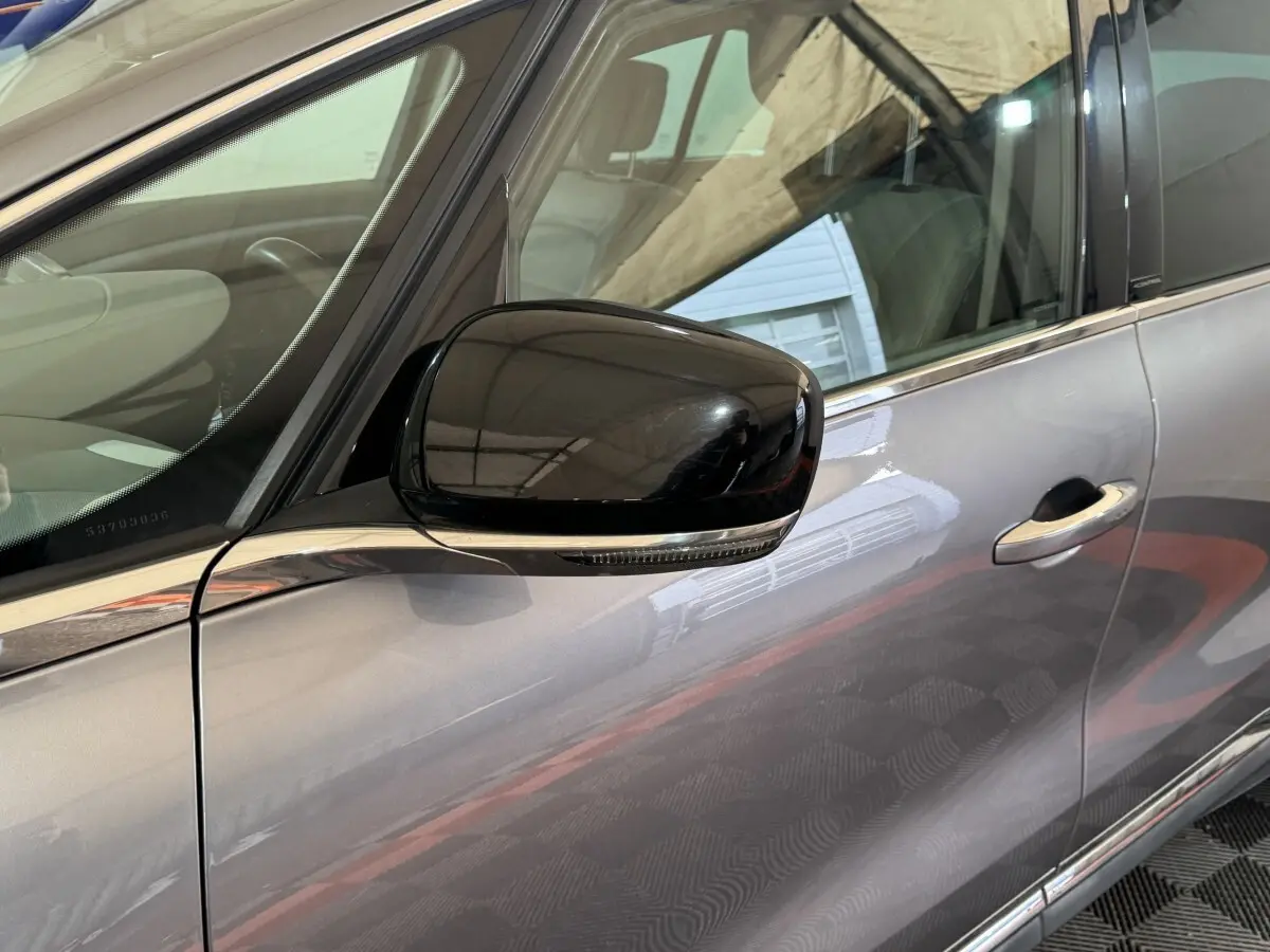 Rétroviseur noir en gros plan côté conducteur sur la porte gris foncé d’un Renault Espace 2015.