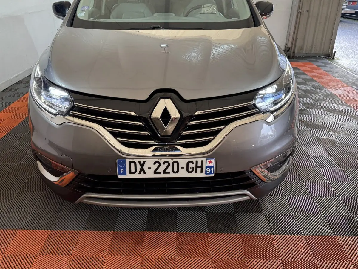 Vue avant d’un Renault Espace Initiale Paris gris foncé avec phares LED allumés et calandre chromée visible.