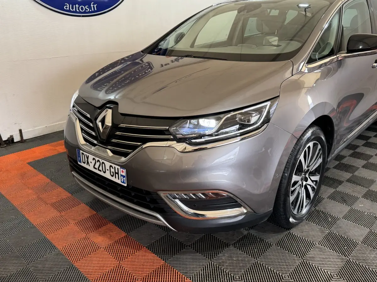 Vue 3/4 avant droit d’un Renault Espace gris foncé avec phares LED et calandre chromée dans un showroom.