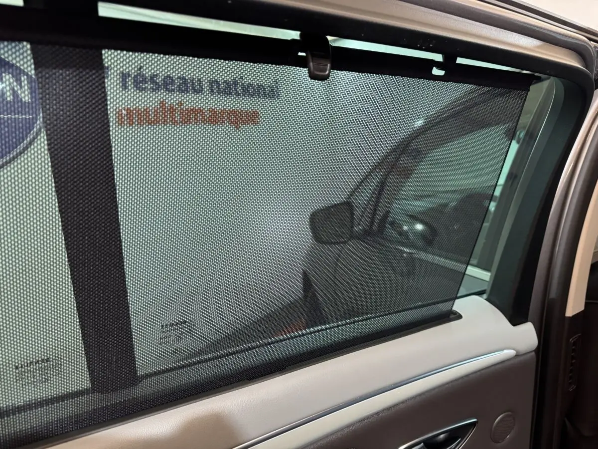 Vue intérieure côté gauche de la porte arrière du Renault Espace gris foncé avec store pare-soleil manuel visible.