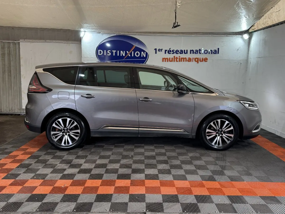 Profil droit d'un Renault Espace gris foncé 2015, avec jantes alliage bicolores et vitres teintées, en intérieur showroom.