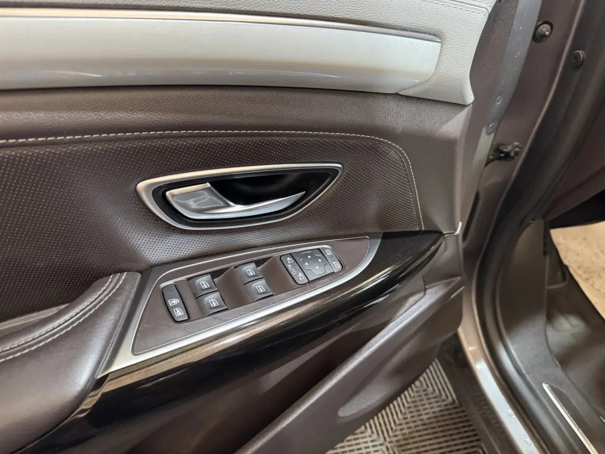 Gros plan sur la porte avant gauche gris foncé de Renault Espace 2015 avec commandes électriques des vitres et poignée chrome.