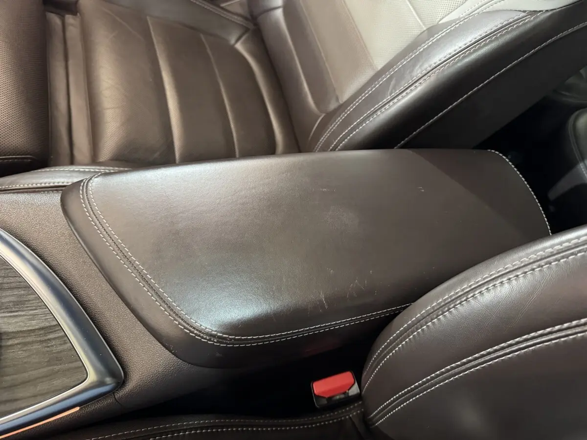 Détail de l'accoudoir central en cuir marron avec surpiqûres blanches dans l'habitacle du Renault Espace gris foncé 2015.