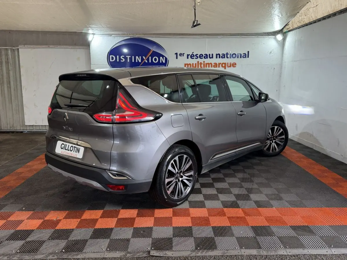 Renault Espace gris foncé vue 3/4 arrière droit, feux arrière LED et jantes alliage visibles en intérieur showroom.