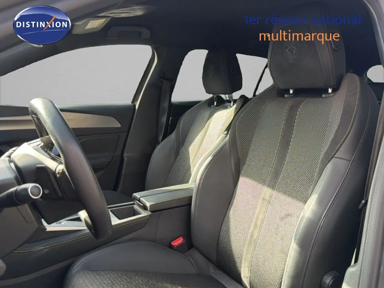 Vue intérieure côté gauche montrant les sièges avant en tissu et cuir noir avec logo Peugeot brodé sur les appuie-têtes.