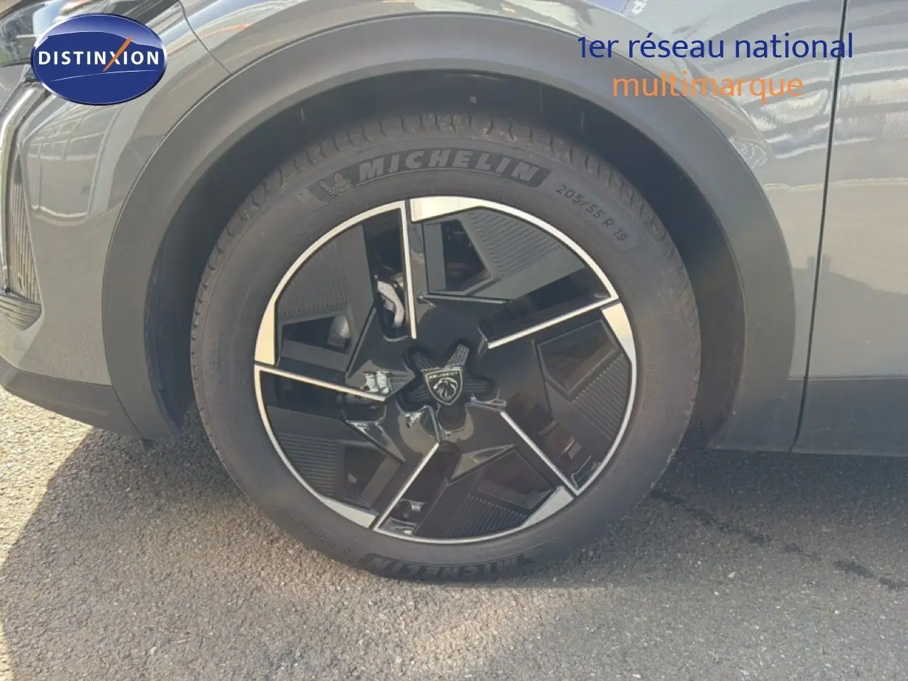 Gros plan sur la roue avant gauche d'une Peugeot 408 gris selenium metal avec jante noire et argentée au design moderne.