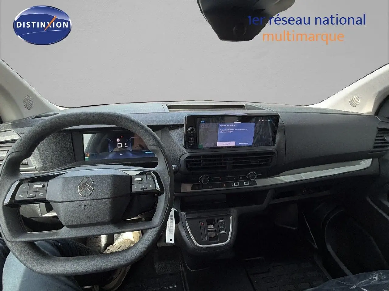 Vue intérieure frontale du tableau de bord du Citroën Jumpy blanc Kaolin avec volant multifonction et écran tactile central.