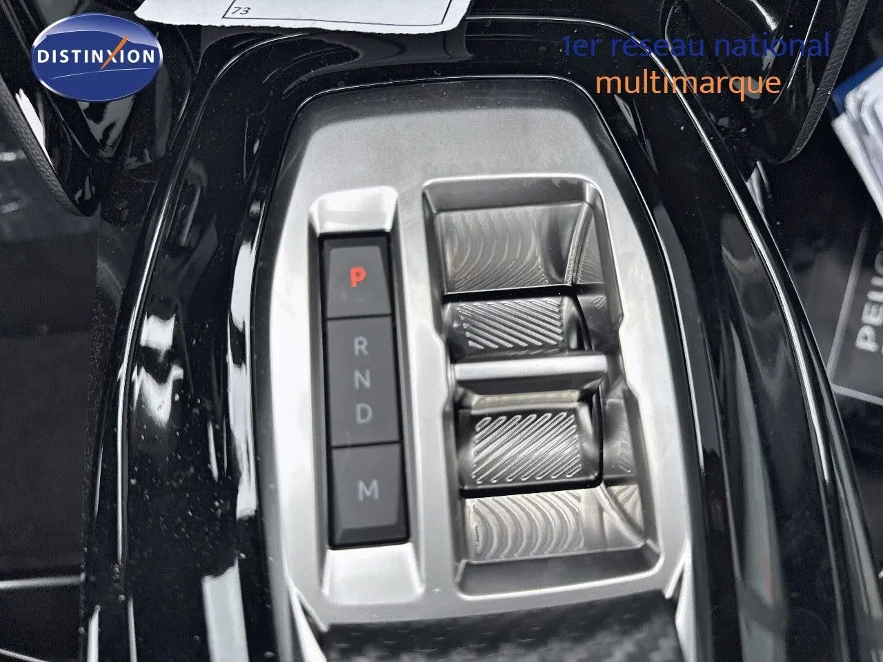 Gros plan sur la console centrale noire du Peugeot 2008 Hybrid 136ch avec sélecteur de boîte automatique et boutons de vitesse.