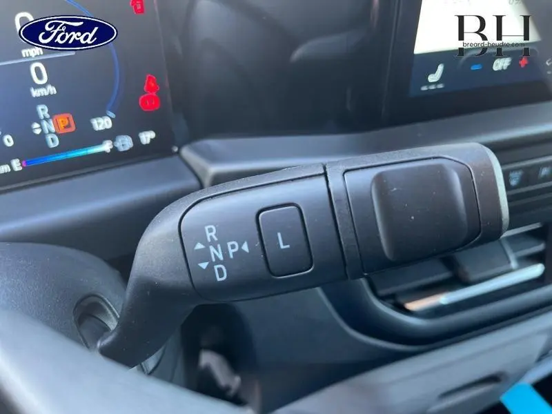 Gros plan sur le levier de boîte automatique du Ford Transit Custom gris, avec tableau de bord numérique en arrière-plan.