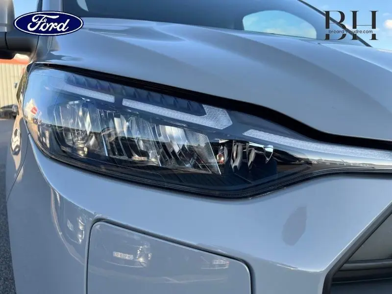 Gros plan sur le phare avant gauche du Ford Transit Custom Fourgon gris Matter Spéciale, soulignant son design moderne.