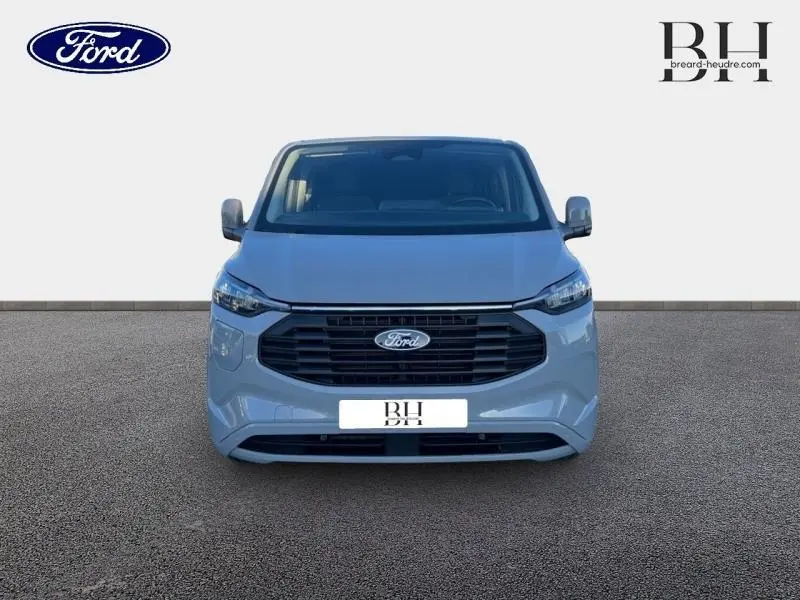 Vue frontale du Ford Transit Custom Fourgon gris Matter Spéciale avec calandre noire et logo Ford centré.