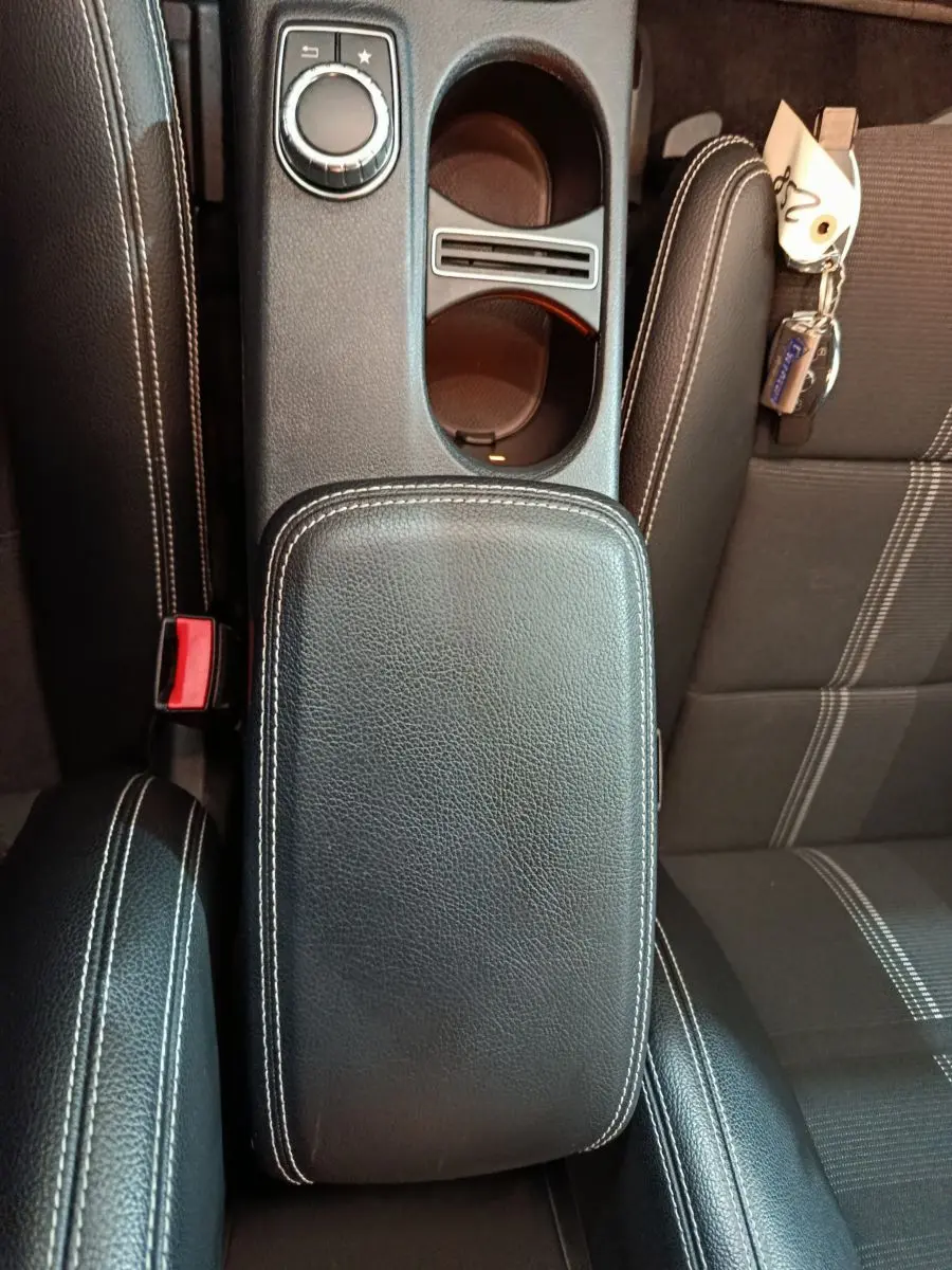Vue plongeante sur la console centrale cuir noir avec surpiqûres blanches et porte-gobelets du Mercedes GLA 200 d gris clair.