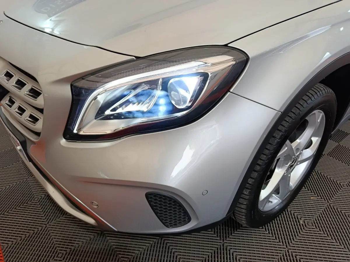 Gros plan sur l'avant droit gris clair du Mercedes GLA 200 d, mettant en valeur le phare LED allumé et la roue.