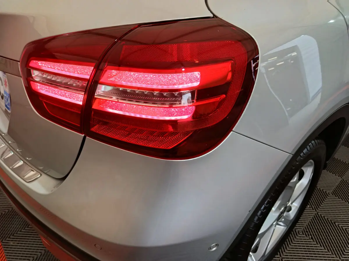 Gros plan sur le feu arrière droit allumé d’un Mercedes GLA 200 d gris clair, avec partie de la roue visible.