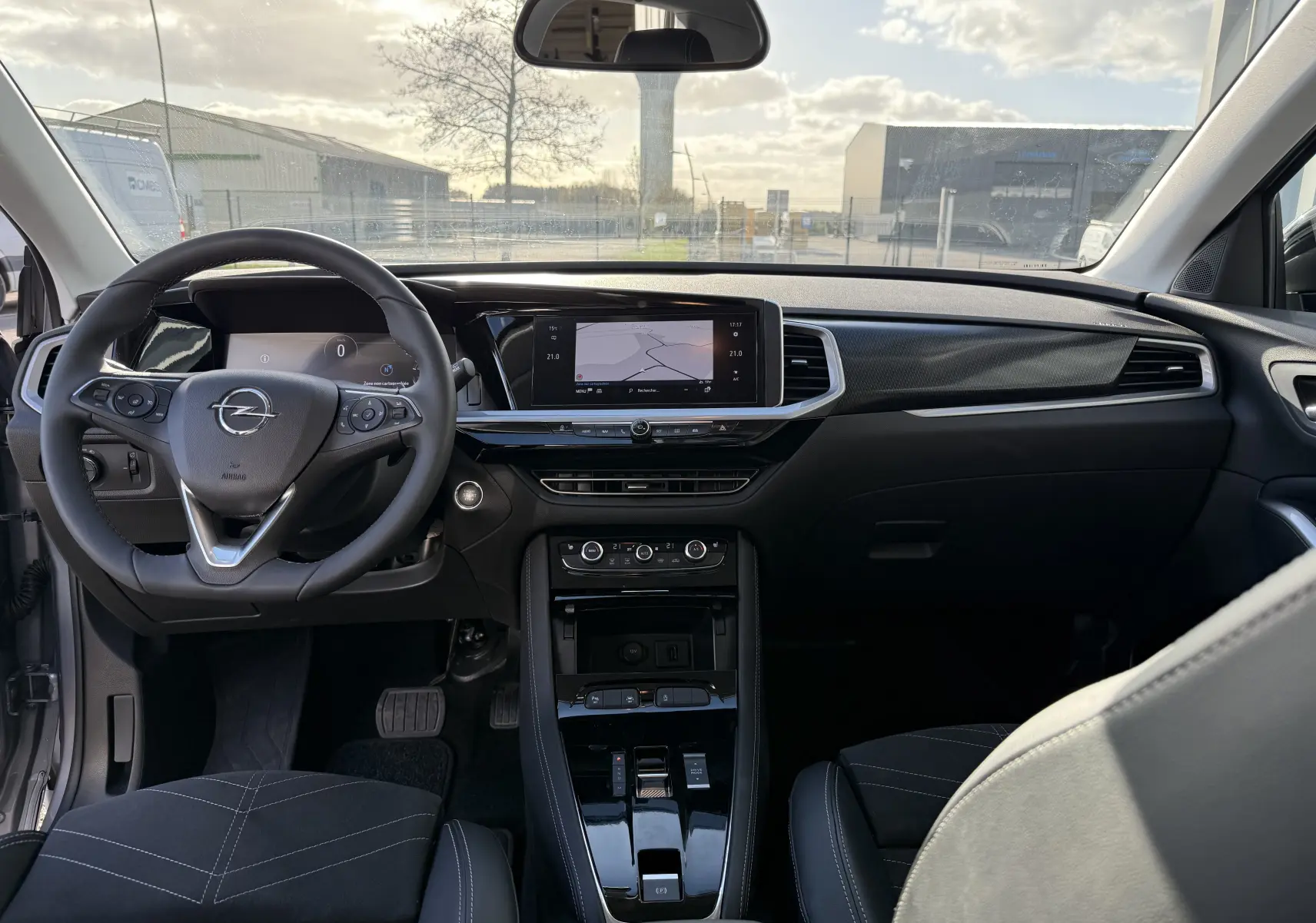 Intérieur de l’Opel Grandland 2024, vue frontale du tableau de bord avec écran tactile et volant multifonction noir.