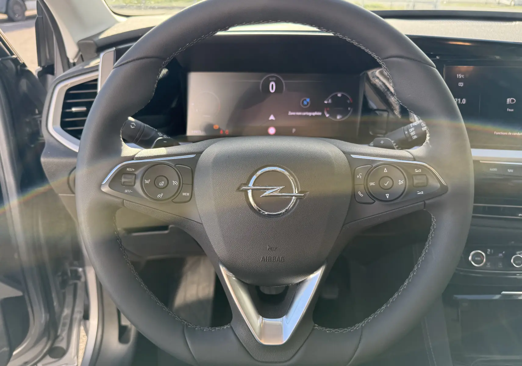 Volant en cuir noir de l'Opel Grandland 2024, avec commandes intégrées et tableau de bord numérique en arrière-plan.