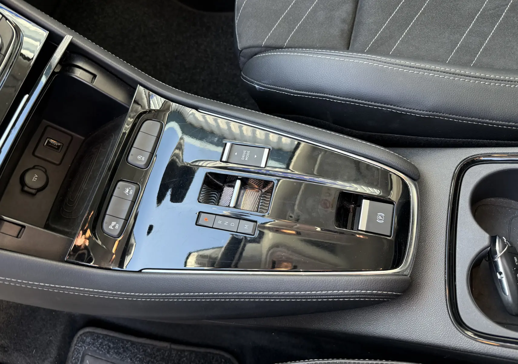 Gros plan sur la console centrale noire brillante de l’Opel Grandland gris Artense avec levier de vitesses automatique et siège en cuir noir.