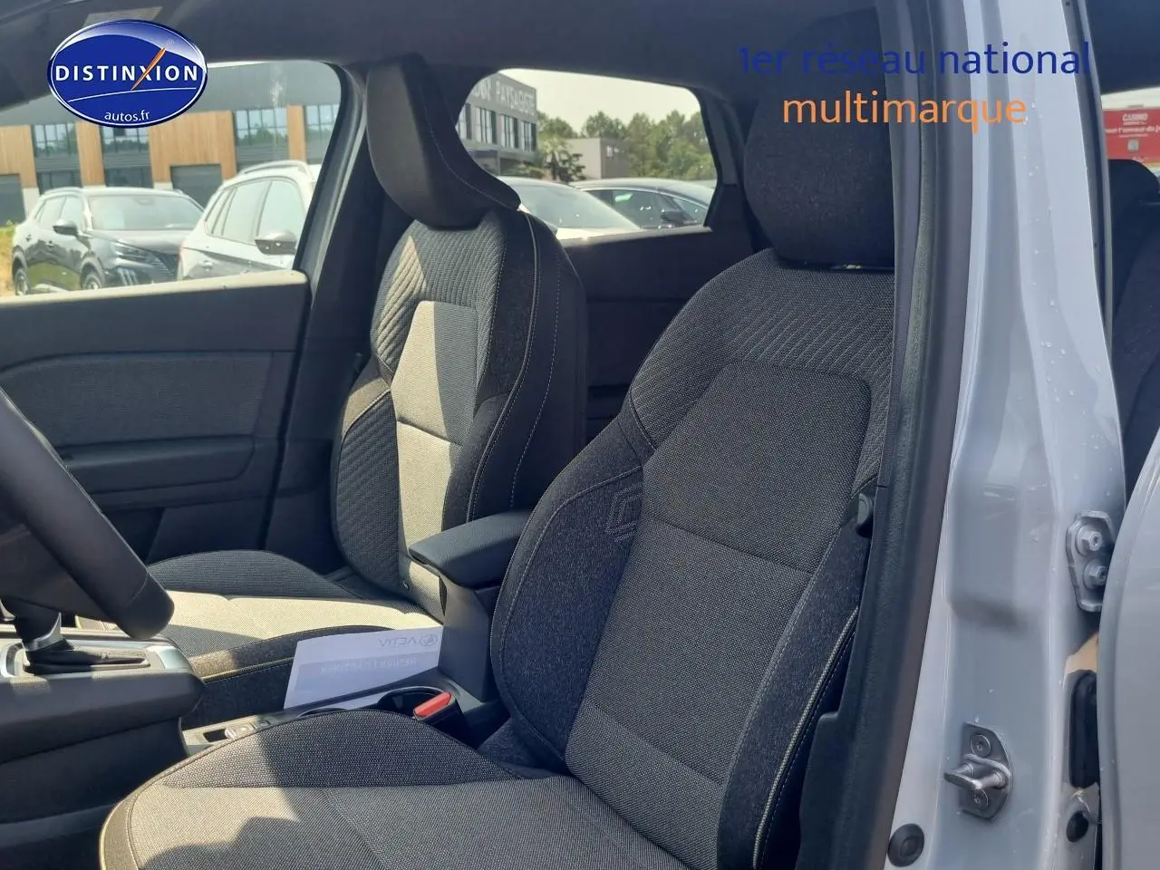 Vue intérieure côté droit du Renault Captur gris rafale 2025, mettant en valeur les sièges tissu et l'accoudoir central.