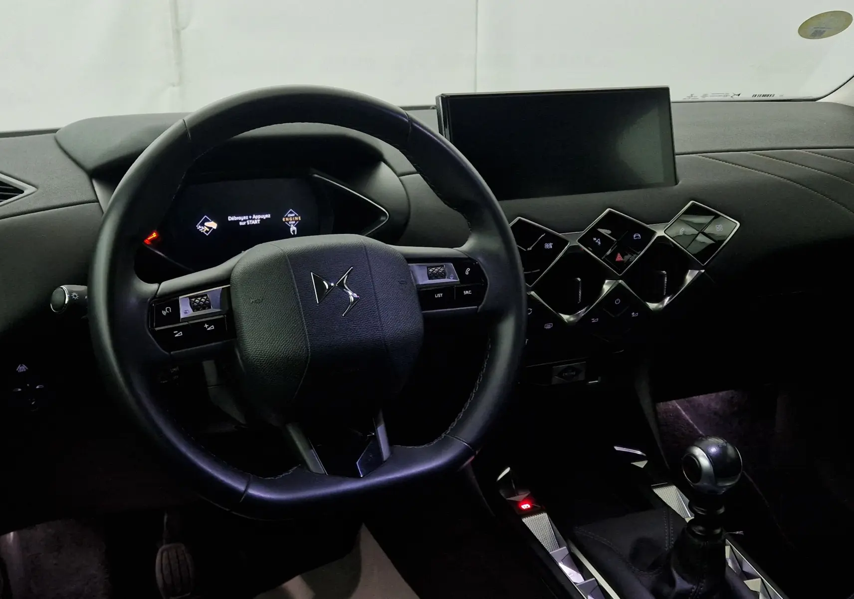 Intérieur du DS3 Crossback 2022 gris platinium, vue centrée sur le volant cuir noir et la console avec commandes géométriques.