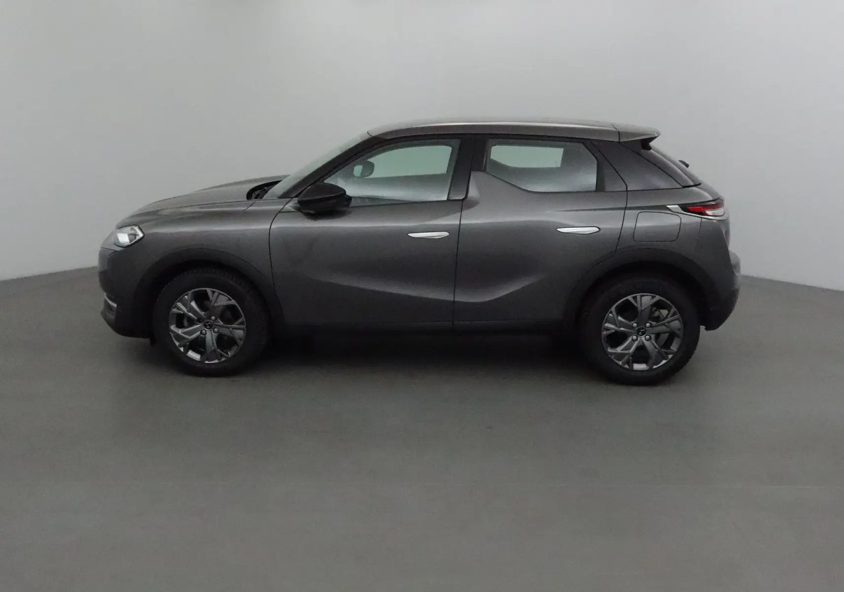 Profil côté gauche d'un DS3 Crossback gris platinium 2022, avec lignes sculptées et toit noir contrastant.