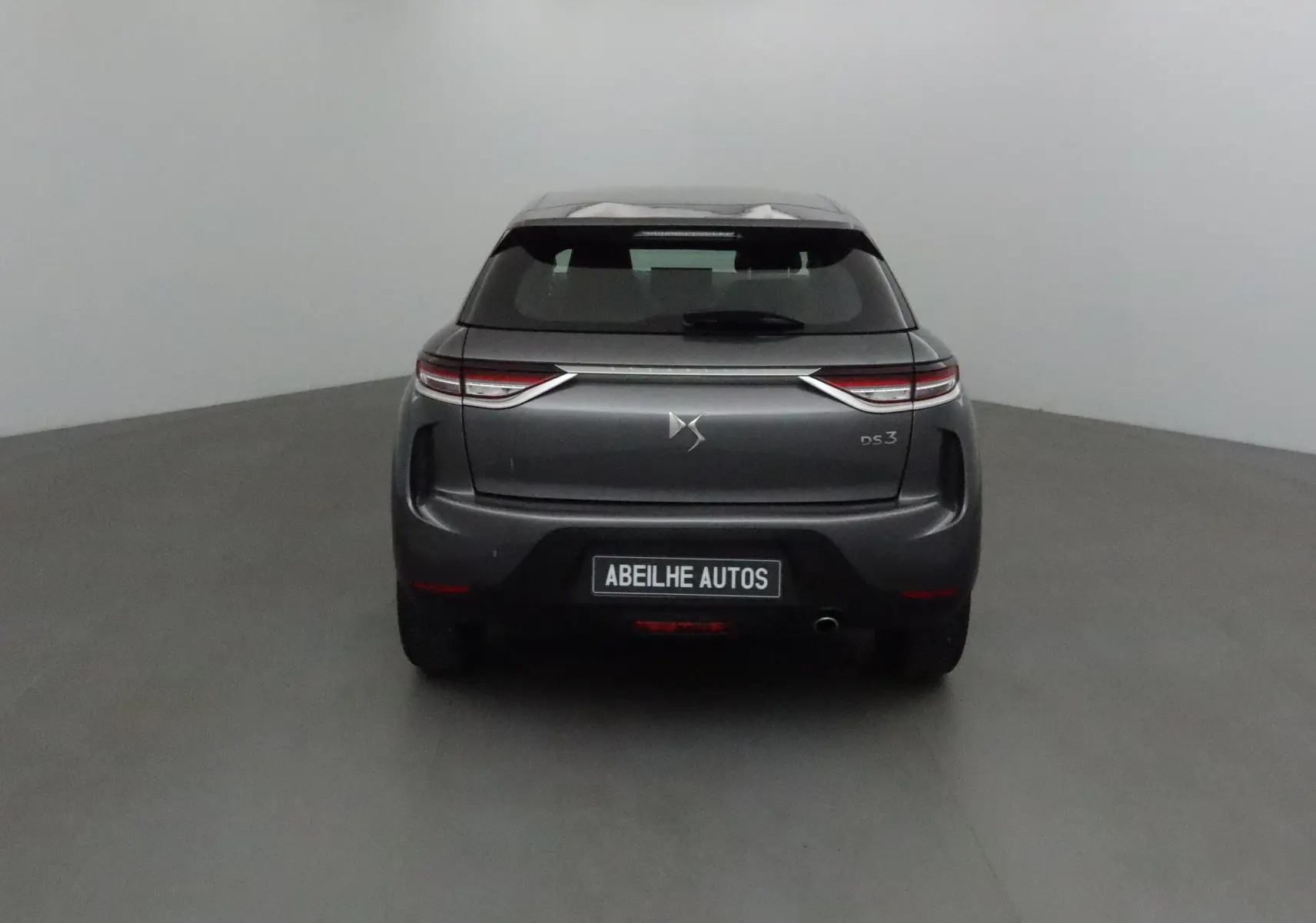 Vue arrière d'un DS3 Crossback gris platinium 2022 avec feux LED et logo DS bien visibles sur fond neutre.
