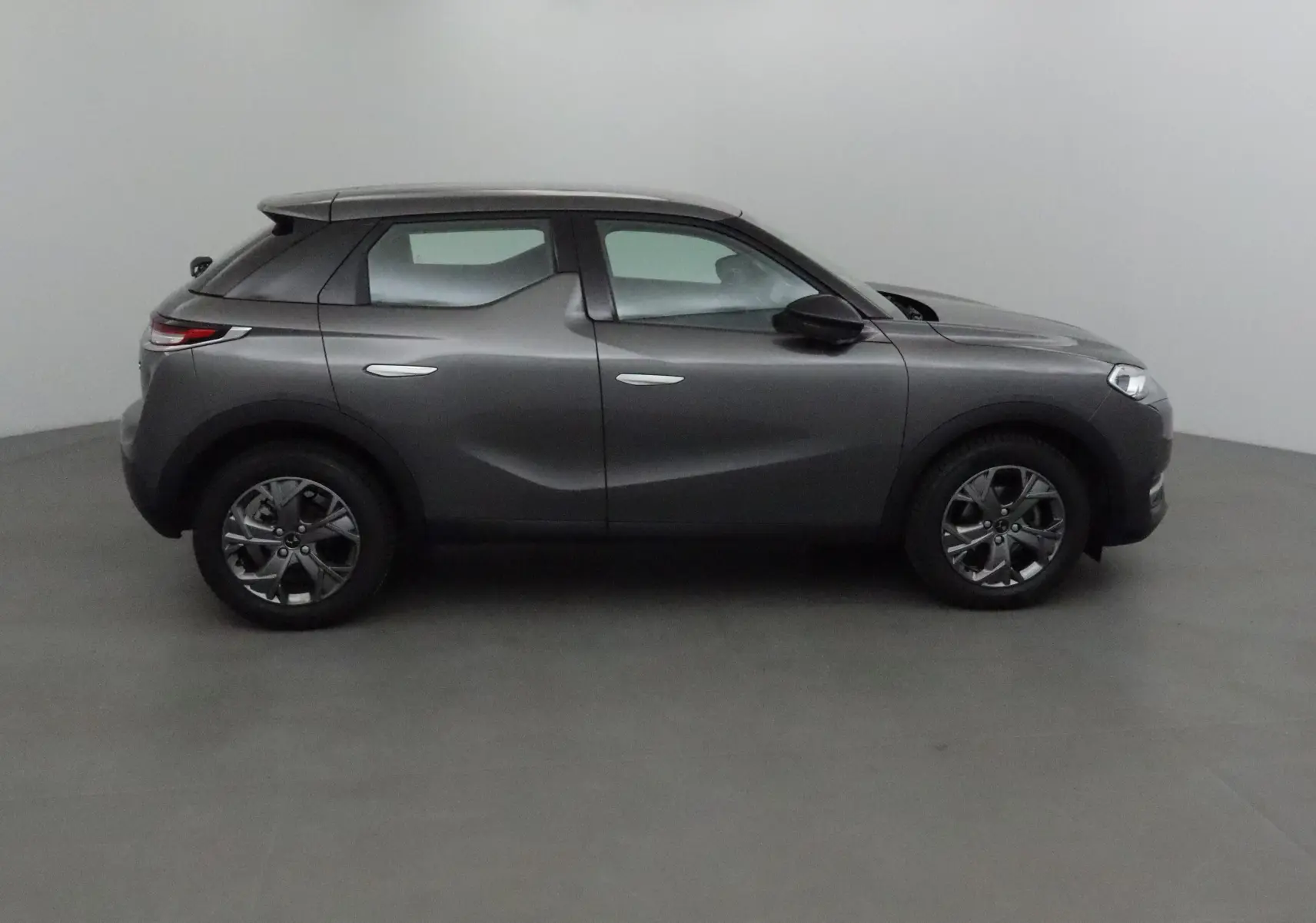 Vue de profil côté gauche d'un DS3 Crossback gris platinium avec jantes alliage foncé et lignes sculptées.